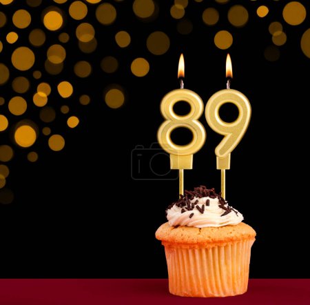 Number 89 birthday candle - Cupcake on black background with out of focus lights
