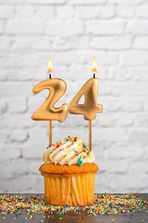Cupcake with number 24 birthday candle - White block wall background
