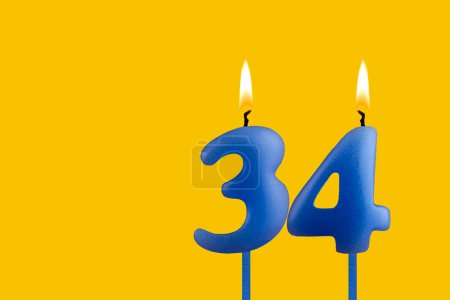 Blue candle number 34 - Birthday on yellow background