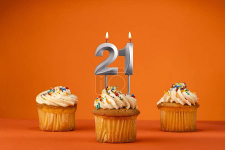 Téléchargez les photos : Bougie numéro 21 - Célébration avec cupcake d'anniversaire sur fond orange - en image libre de droit