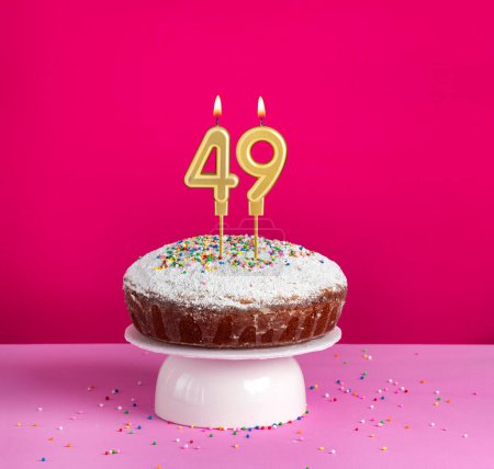 Birthday cake with number 49 candle on pink background