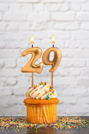 Golden birthday candle number 29 with cupcake - White block wall background