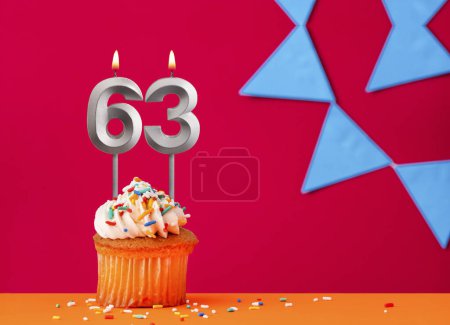 Nummer 63 Kerze mit Geburtstagskuchen auf rotem Hintergrund mit blauem Wimpel