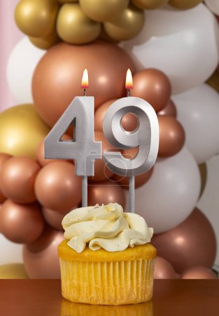 Cupcake con vela de cumpleaños sobre fondo de globos - Número 49