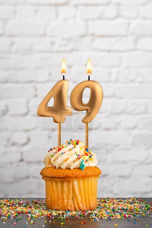 Golden birthday candle number 49 with cupcake - White block wall background