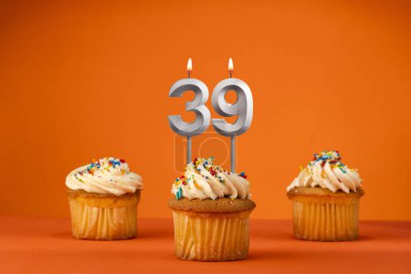 Téléchargez les photos : Bougie numéro 39 - Célébration avec cupcake d'anniversaire sur fond orange - en image libre de droit