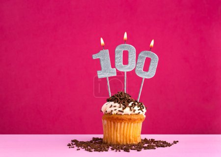 Geburtstagsfeier mit Kerze Nummer 100 - Schoko-Cupcake auf rosa Hintergrund