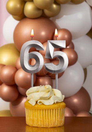 Cupcake con vela de cumpleaños sobre fondo de globos - Número 65