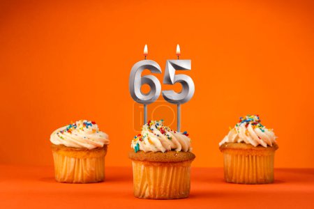Kerze Nummer 65 - Feier mit Geburtstagskuchen auf orangefarbenem Hintergrund
