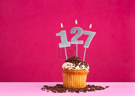 Geburtstagskuchen mit Kerze Nummer 127 - Geburtstagskarte auf rosa Hintergrund