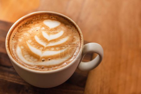 Téléchargez les photos : Une tasse de cappuccino avec latte art sur fond d'espace en bois. Tonifiant tendance. Composition minimale, vue de dessus, espace de copie plat pour votre texte. - en image libre de droit