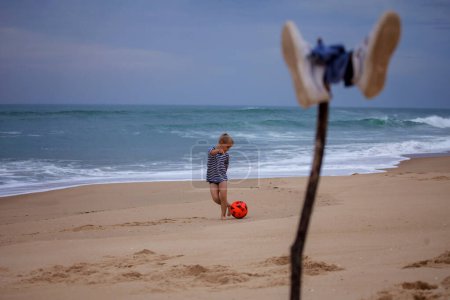 Photo for A small football fan barefoot repeats the tricks of his idol right on the ocean. Football everywhere. Sport, soccer, fandom. The football festival is coming - Royalty Free Image
