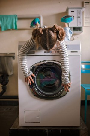 Photo for Eco-conscious teenage girl waits in common laundry. Sustainability and responsible living. Efforts to save resources, conserve water, energy, and money. Eco-lifestyle in action - Royalty Free Image