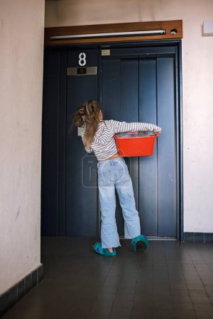 Photo for Teenage girl with a laundry basket going to common laundry. Concept of ecology, sustainability, care for environment, as well as saving money and natural resources - Royalty Free Image