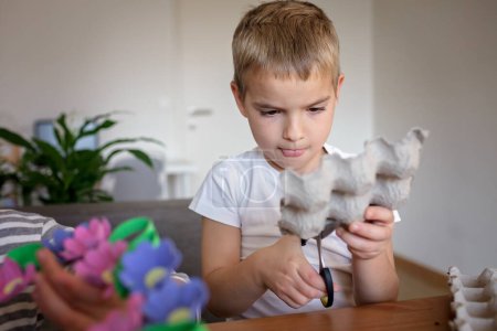 Projet de bricolage avec des enfants, un carton d'?ufs est transformé en couronne de fleurs de Pâques. Créativité et durabilité associées à un mode de vie zéro déchet. Réduire, réutiliser et recycler