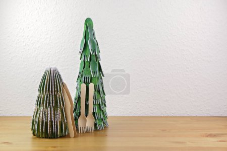 Un arbre de Noël bricolage créatif fabriqué à partir de fourchettes et de cuillères en bois jetables. Concept de réutilisable, zéro déchet, et un décor écologique avec les enfants. Espace texte, fond festif éco-conscient