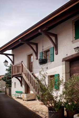 Foto de Una casa de pueblo rústica en Europa, con vigas de madera, persianas verdes y un pintoresco balcón, ubicado en una calle serena. - Imagen libre de derechos