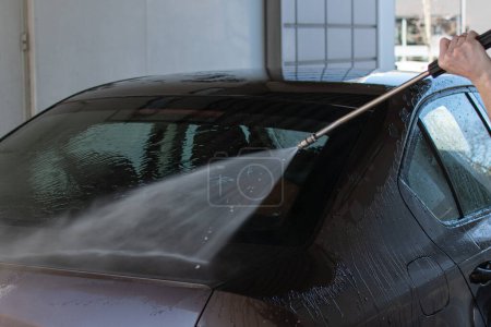 lavado de coches con una pistola de pulverización está siendo rociado en el parabrisas