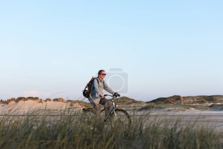 young woman on a bicycle rides along the beach in Sankt Peter-Ording