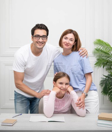 Porträt einer glücklichen Familie mit einer kleinen Tochter, die zu Hause studiert. Heimerziehung und Eltern unterstützen Konzept