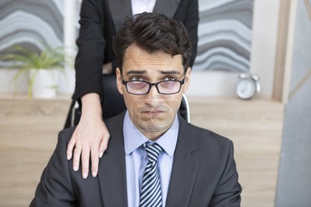 Ein junger gutaussehender Mann fühlt sich unwohl, weil seine Chefin sich im Büro unangemessen benimmt. Belästigung am Arbeitsplatz