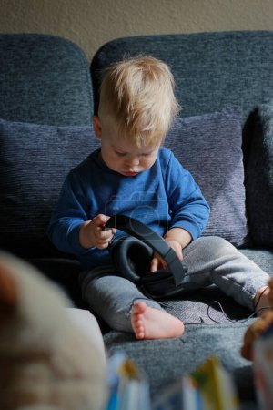 Foto de Niño jugando con auriculares en el sofá. Foto de alta calidad - Imagen libre de derechos