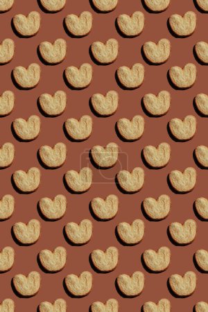 Foto de Seamless pattern of heart shaped cookies on brown background. High quality photo - Imagen libre de derechos