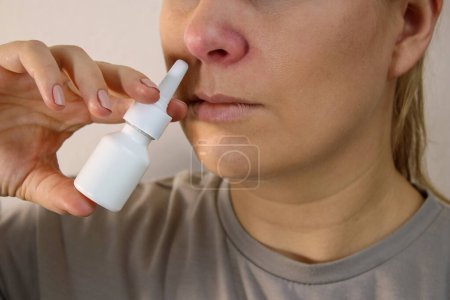 Téléchargez les photos : Gros plan de la femme malade au nez rouge à l'aide d'un spray nasal, fond flou avec espace de copie - en image libre de droit