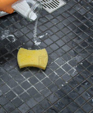 Foto de Primer plano de las manos de las mujeres vertiendo bicarbonato de sodio en el piso de la ducha para limpiar, concepto de limpieza ecológica - Imagen libre de derechos