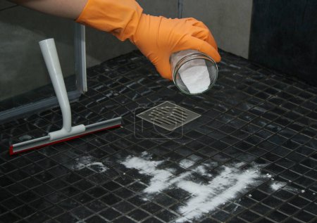 Foto de Primer plano de las manos de las mujeres vertiendo bicarbonato de sodio en el piso de la ducha para limpiar, concepto de limpieza ecológica - Imagen libre de derechos
