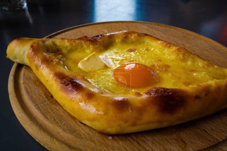 Photo for Traditional Georgian cuisine - Adjarian khachapuri on a wooden board. Ready-to-eat baking - Royalty Free Image