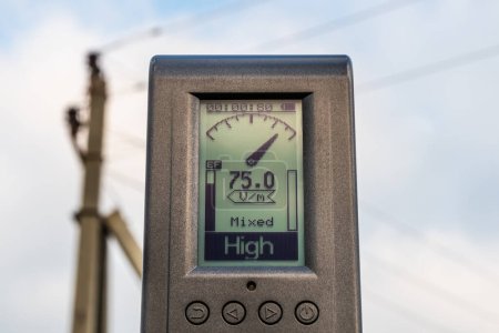 Photo for The measuring device shows a high level of electric field strength near a high-voltage power line - Royalty Free Image