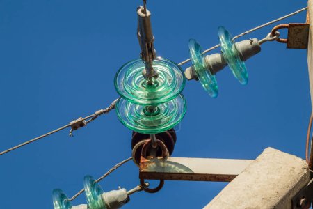 Glass insulators and wires of a high-voltage overhead power line against a background of blue sky on a sunny day