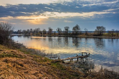Szenische Ansicht des Flusses Seversky Donez in der Landschaft an einem Frühlingsmorgen. Landschaft des Flusses Siwerskyi Donez mit einem kleinen hölzernen Steg - ein Ort zum Angeln