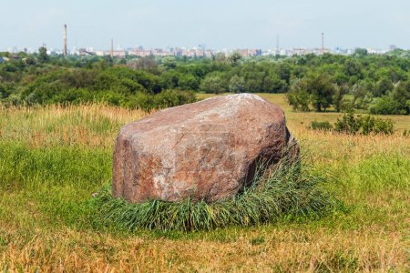 Large ritual stone on the grass on the hill. Cult stone and territory of an ancient settlement found in Kharkiv city, Ukraine