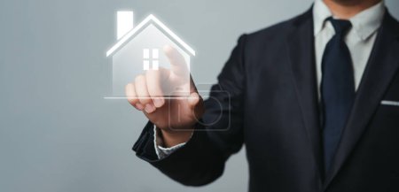 Geschäftsmann zeigt auf Haus-Ikone Ein Makler für Immobilieninvestitionen für den Kauf von Verkauf und Vermietung, der finanzielle Anlageberatung für Wohnungen anbietet, die den Bedürfnissen der Familie und des Kunden entsprechen