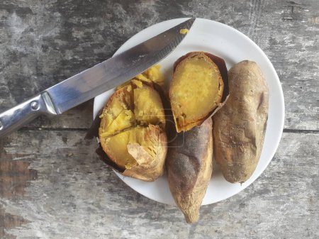 Cilembu Süßkartoffel mit Honig auf einem kleinen Teller gebraten. Holztischhintergrund. Cilembu Süßkartoffel ist eine lokale Süßkartoffelsorte aus Cilembu Dorf.