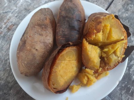 Patata dulce Cilembu asada con miel en un plato pequeño. Fondo de tabla de madera. La batata de Cilembu es una raza local de cultivar batata de la aldea de Cilembu.