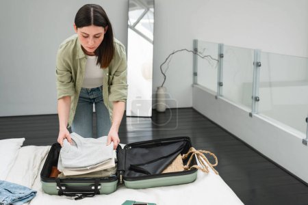 Photo for Young brunette woman packing suitcase for a solo traveling abroad. Summer vacation. Traveling overseas. - Royalty Free Image