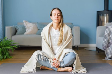 Young woman practicing meditation self care at home. Concept of mental health and women's wellness, mindfulness.