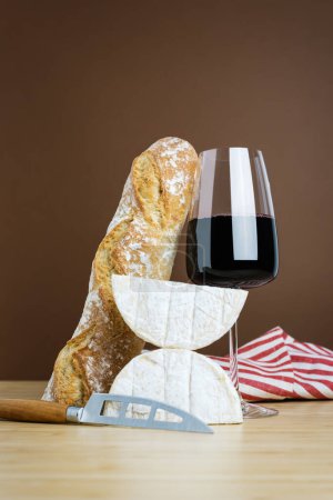 Photo for Minimalistic composition of a glass of red wine, a baguette, and camembert cheese. - Royalty Free Image