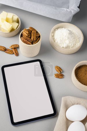 Großaufnahme von Brownie-Zutaten und Tablette auf einer grauen Oberfläche in der modernen Küche. Kulinarischer Blog.