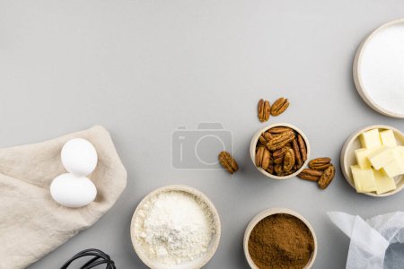 Brownie recipe ingredients and kitchen utensils on gray background, top view.
