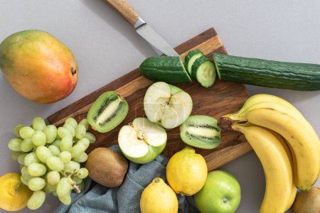 Photo for Fresh fruits grapes, lemons, cucumbers, bananas, mangoes, kiwi, and apples on a cutting board. - Royalty Free Image