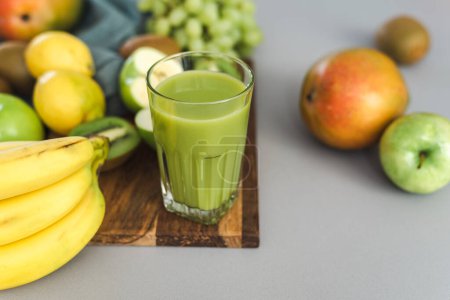 Photo for Freshly made a green fruit smoothie and some fruit on the kitchen table. - Royalty Free Image
