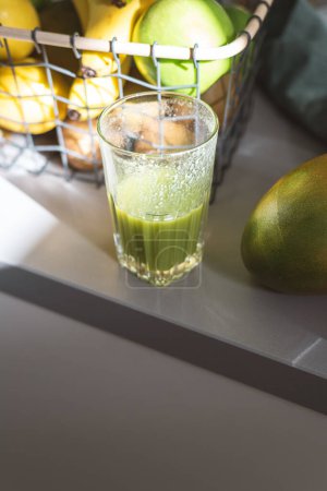 Foto de Un vaso a medio terminar de batido de frutas verdes en la cocina por la mañana. - Imagen libre de derechos