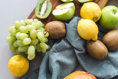 Photo for Fresh fruits grapes, lemons, bananas, mangoes, kiwi, and apples on a cutting board. - Royalty Free Image