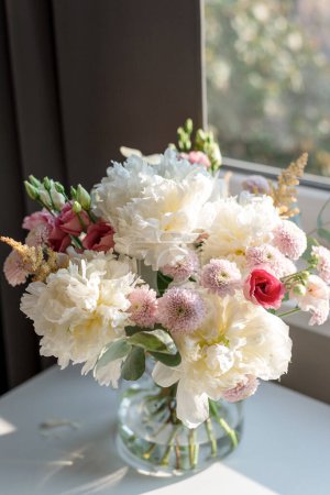 Téléchargez les photos : Un bouquet de fleurs sur la table à la lumière du coucher du soleil. - en image libre de droit