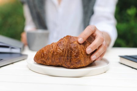Foto de Mano femenina irreconocible sostiene un croissant recién horneado. - Imagen libre de derechos