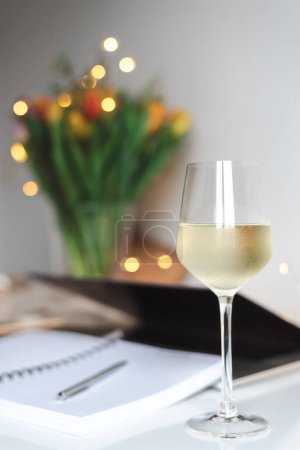 Una copa de vino blanco en el escritorio.
